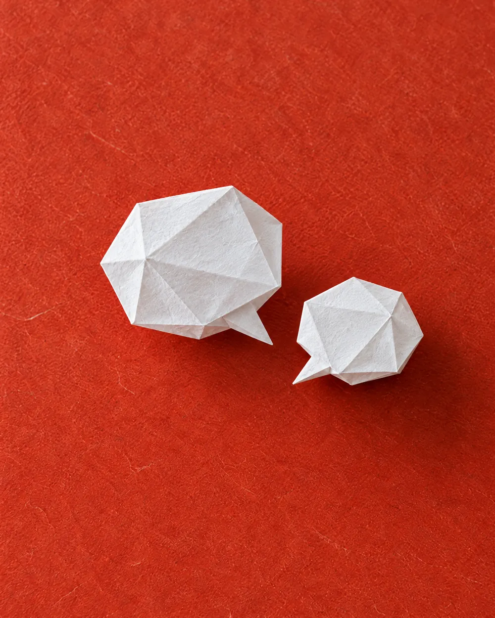 Two speech bubbles folded from white paper, facing each other.